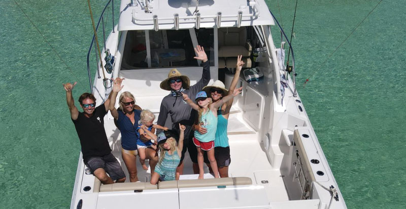 A family waves aboard their Pursuit OS 325 from Pursuit magazine EXPLORE.