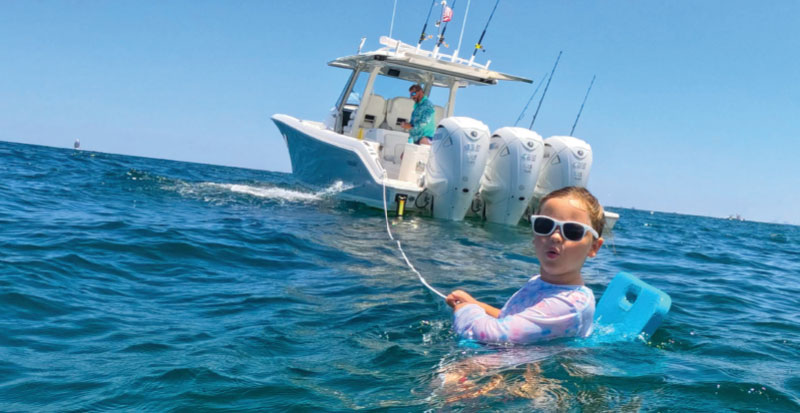 A little girl plays in the water off the stern of a Pursuit S 378 Center Console from Pursuit magazine EXPLORE.