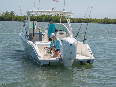 A woman placing a line in a transom storage compartment on a new D 246 Pursuit Luxury Dual Console boat.