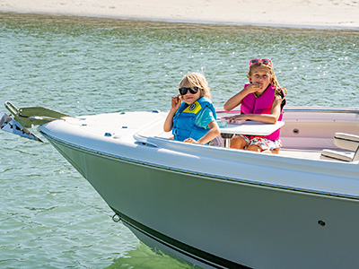 Children have a snack at a bow table on a 25’ D 246 Pursuit Luxury Dual Console boat.