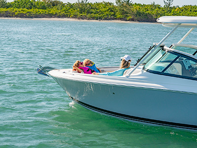 After a day of boating, a family relaxes on a sun pad aboard a D 246 Pursuit Luxury Dual Console boat.