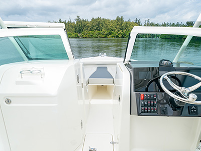 View of the river through the molded fiberglass windshield frame with tempered glass windshield and center walk-through door on a new D 246 Pursuit Luxury Dual Console boat.