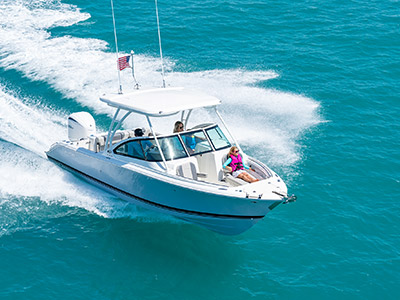A girl enjoys riding on a bowrider D 246 Pursuit Luxury Dual Console boat with hardtop.