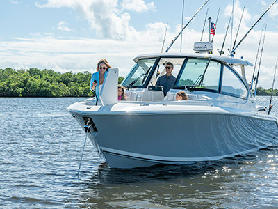 A woman lowers an anchor on a Pursuit D 306 Luxury Dual Console boat.