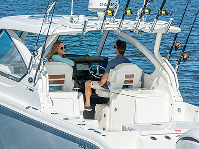 A couple sits on a Pursuit D 306 Luxury Dual Console boat rigged for fishing.
