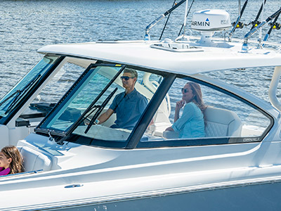 A couple sitting in the helm and companion seats on a Pursuit D 306 Luxury Dual Console boat.