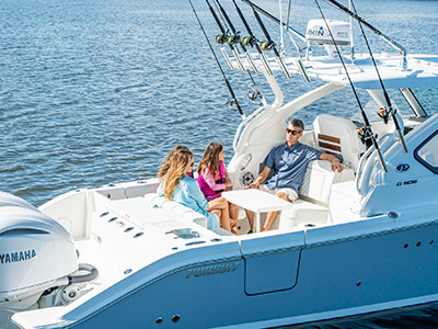 A family sits around a removable table on a Pursuit D 306 Luxury Dual Console boat.