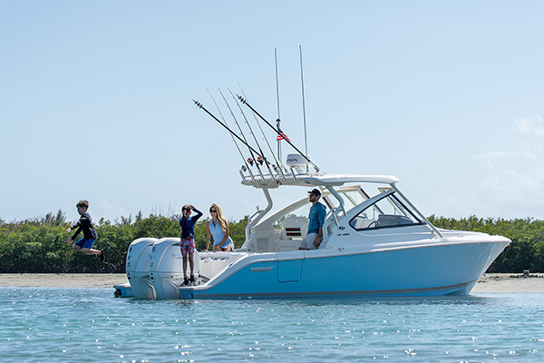 Boys jumping into the water from the extended transom platforms of a 28’ {pursuit Dual Console.