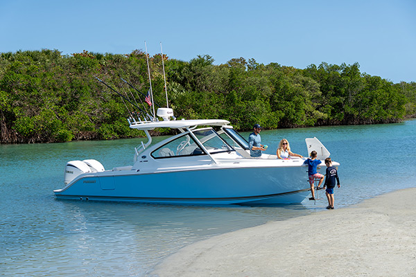 Boys climb down bow boarding ladder on a 28’ Pursuit Dual Console Boat.