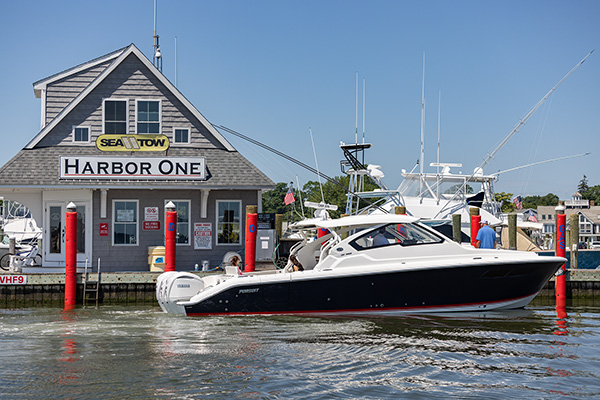 A Pursuit boat near the building with signs for "Sea Tow" and "Harbor One"