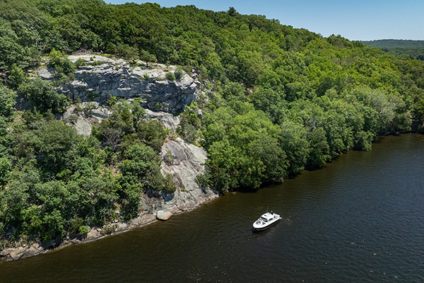 Aerial view of the Pursuit DC 365 Dual Console and a rocky slope with lush green vegetation.