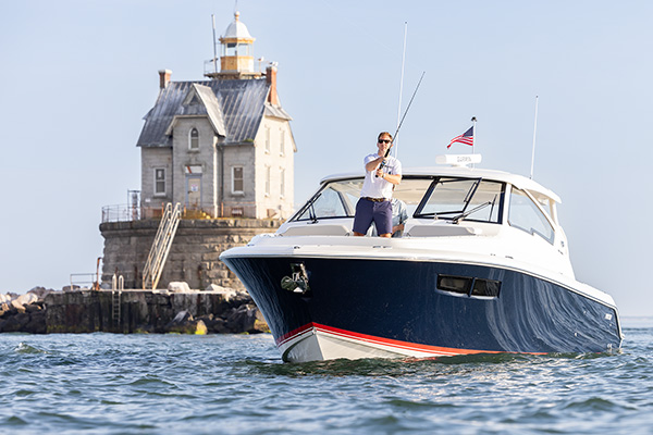 A man is fishing aboard the Pursuit DC 365 by the Race Rock Lighthouse.