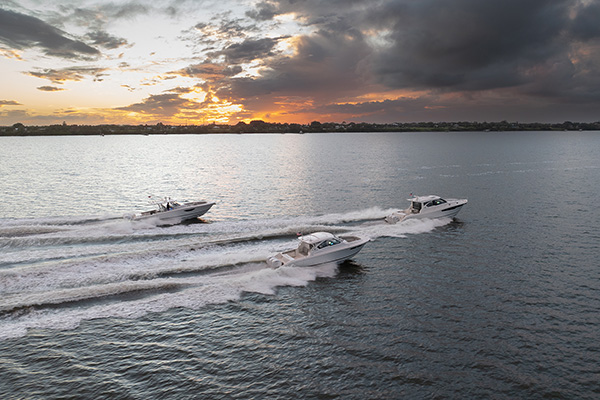 Side view of Pursuit Boats Flagship models running during sunset.