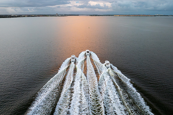 Aerial view of Pursuit Boats S 428 Sport Center Console OS 445 Offshore and DC 365 running in smooth water toward the sun.