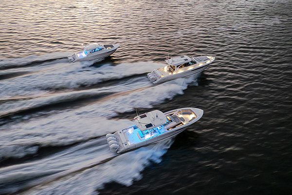 Pursuit Boats fleet of flagship models lit up and running at dusk.