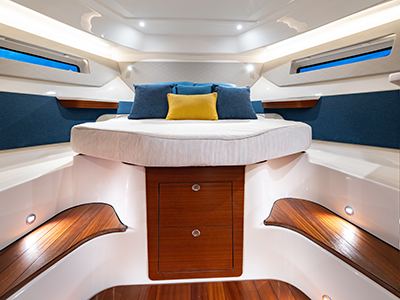 Convertible bed with pillows raised on offshore Pursuit cabin boat.