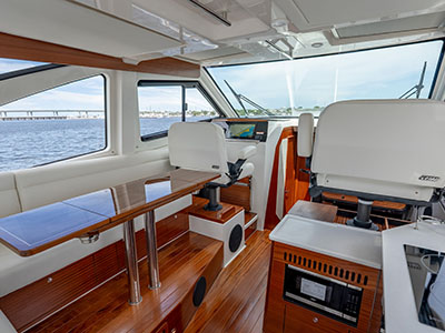 Salon of a Pursuit OS 445 looking aft toward the galley, teak joinery and dinette.