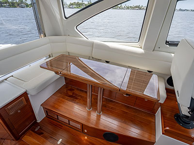 Salon dinette of a Pursuit OS 445 with a glass-topped table and teak flooring.