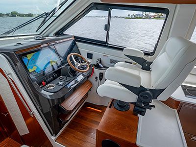 Helm station of a Pursuit OS 445 with the wheel, Garmin displays, and twin helm seats.