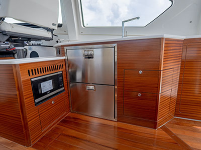Galley of a Pursuit OS 445 with microwave, stainless refrigerator drawers, and teak cabinetry.