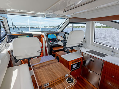 Interior overview of a Pursuit OS 445 salon showing helm seats, galley, and dinette.