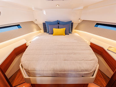 Forward cabin berth aboard a Pursuit OS 445 with accent pillows and hull portholes.