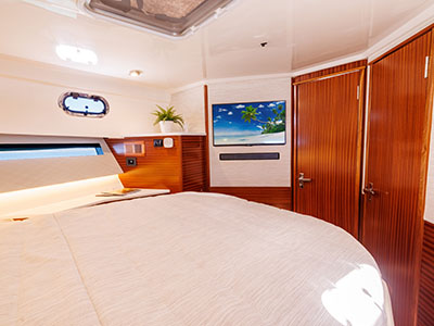 Cabin of a Pursuit OS 445 with a wall-mounted television and teak doors.