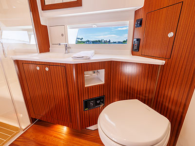 Head compartment aboard a Pursuit OS 445 with sink, vanity, and teak joinery.