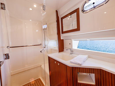 Head with separate shower aboard a Pursuit OS 445, mirror and porthole above the vanity.