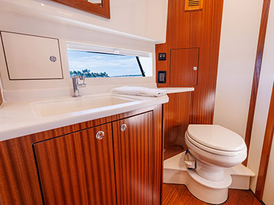 Head compartment of a Pursuit OS 445 with vanity, sink, and hull window.
