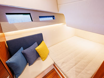 Berth aboard a Pursuit OS 445 with accent pillows and hull windows.