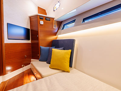 Cabin seating aboard a Pursuit OS 445 with a television and accent pillows.