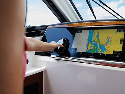 A hand operating the Garmin chartplotter at the helm of a Pursuit OS 445.