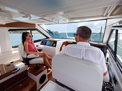 Two people at the interior helm of a Pursuit OS 445 underway.