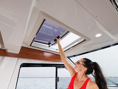 A woman reaching up to open the overhead sunroof of a Pursuit OS 445.