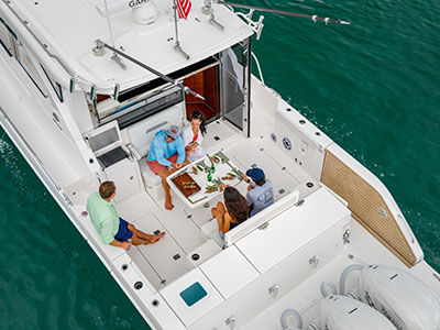 Aerial view of a group dining at the cockpit table aboard a Pursuit OS 445 at anchor.