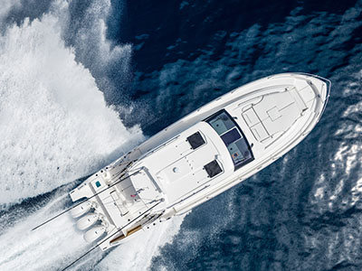 Aerial view of a Pursuit OS 445 in a hard turn, throwing white water across dark blue open ocean.