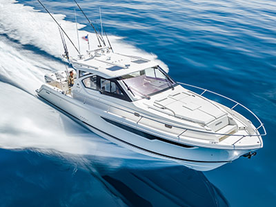 Pursuit OS 445 running on deep blue water, bow quarter view with outriggers deployed and US flag flying.