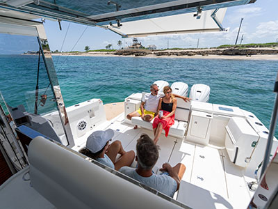 View aft from the cockpit of a Pursuit OS 445 toward people seated at the transom and swim platform.