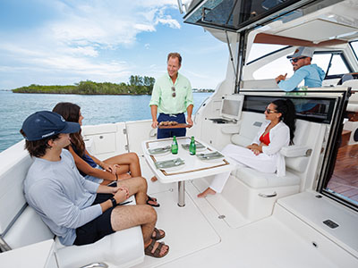 Group dining at the cockpit table of a Pursuit OS 445 anchored near a mangrove island.