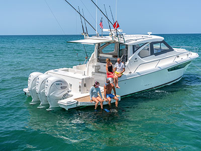 Group seated on the swim platform of a Pursuit OS 445 anchored in turquoise water.