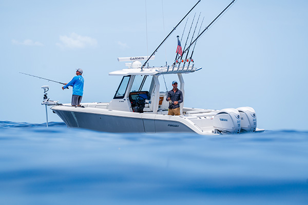 Two men fishing from opposite ends of a Pursuit S 288 center console boat, viewed at water level with the dual outboard engines visible at the stern.