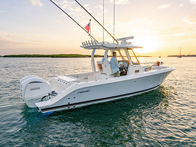 Pursuit center console boat at sunset with two men near the helm and a woman seated at the stern with drinks on a small table.