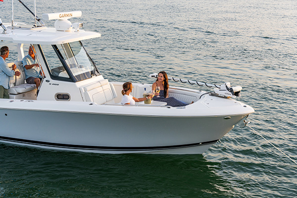 Pursuit S 288 center console boat with two women seated at the bow sharing wine, and two men visible near the helm behind them.