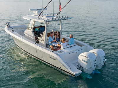 Pursuit center console boat anchored on calm water with four people seated around a table sharing wine in the cockpit.