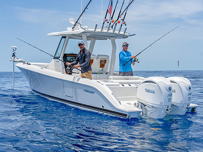 Pursuit S 288 center console boat with two men fishing, rods bent, and dual Yamaha outboard engines visible at the stern.