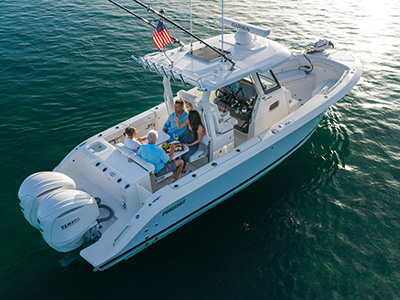 Pursuit center console boat anchored on calm water at golden hour with four people seated around a table with food and drinks in the cockpit.