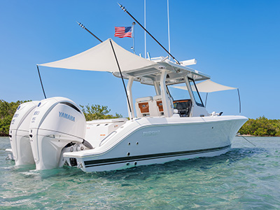 Pursuit center console boat at rest with twin shade canopies extended over the cockpit and dual Yamaha outboard engines visible at the stern, a mangrove shoreline in the background.