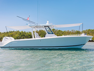 Pursuit S 288 center console boat anchored near a mangrove shoreline with both bow shade canopies extended.