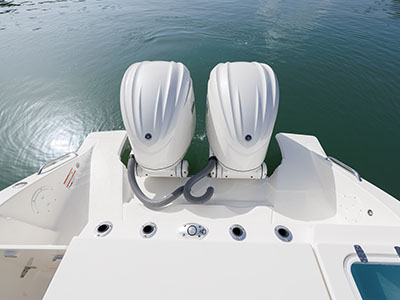 View from the stern looking up at twin Yamaha outboard engines mounted on a Pursuit boat, with rod holders and a fuel fill visible on the transom below.
